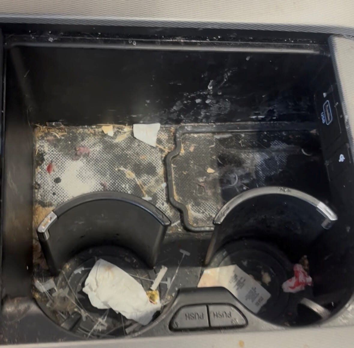 Console Before Cleaning Dirty vehicle center console and cup holders before interior detailing, with crumbs, dust, and debris visible.