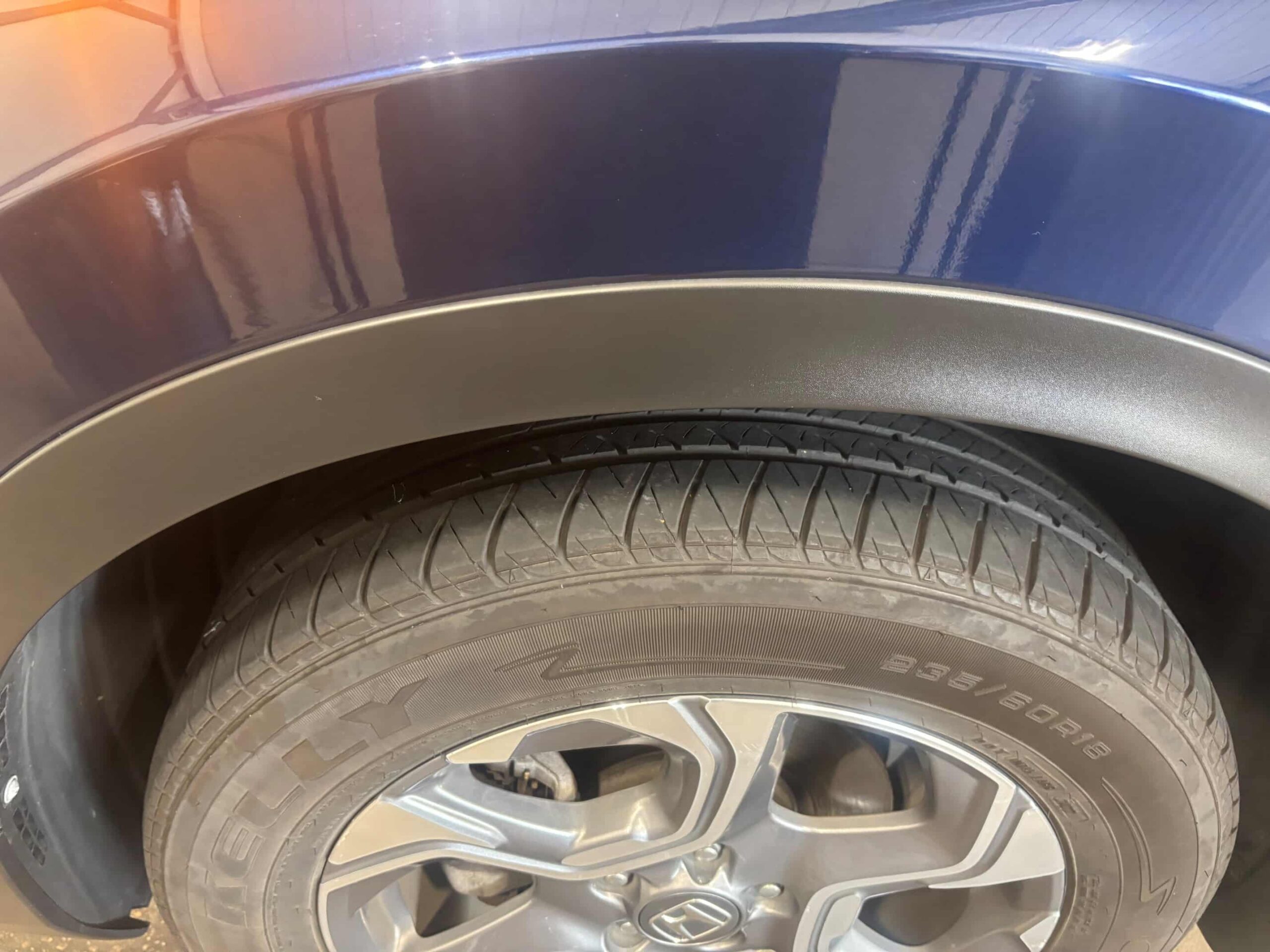 Restored black plastic trim around a vehicle wheel well after treatment, showing a darker refreshed finish.