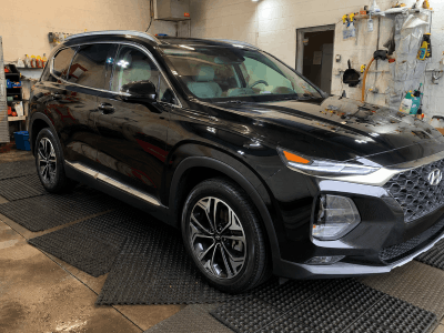 Black SUV after paint enhancement, showing a clean, glossy exterior finish inside a detailing garage.